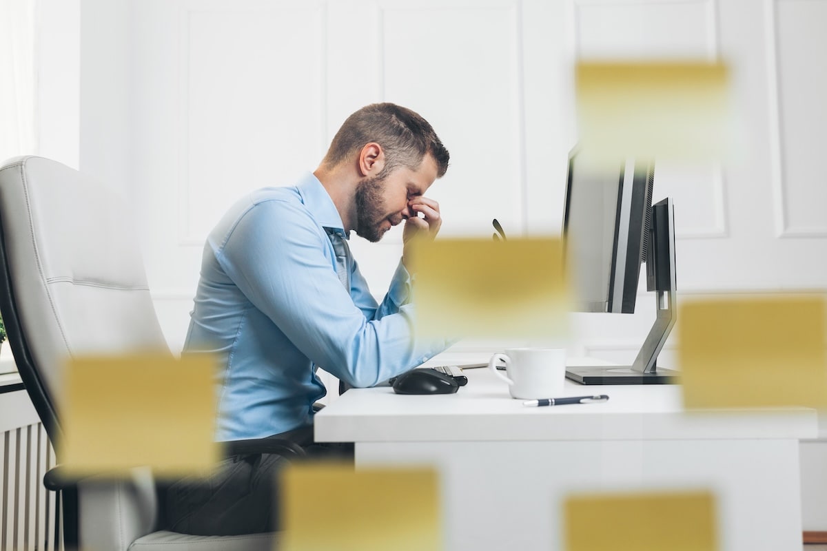 Tired businessman from heavy workload sitting at the desk